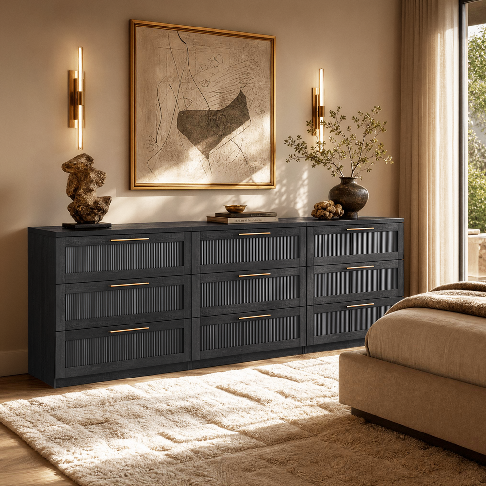 Three dark dressers arranged side by side, with vertically ribbed drawer panels and gold-tone handles in a bedroom