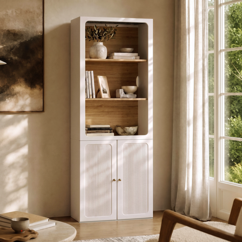White bookcase with wood-tone open shelves and fluted lower doors beside a sunlit window