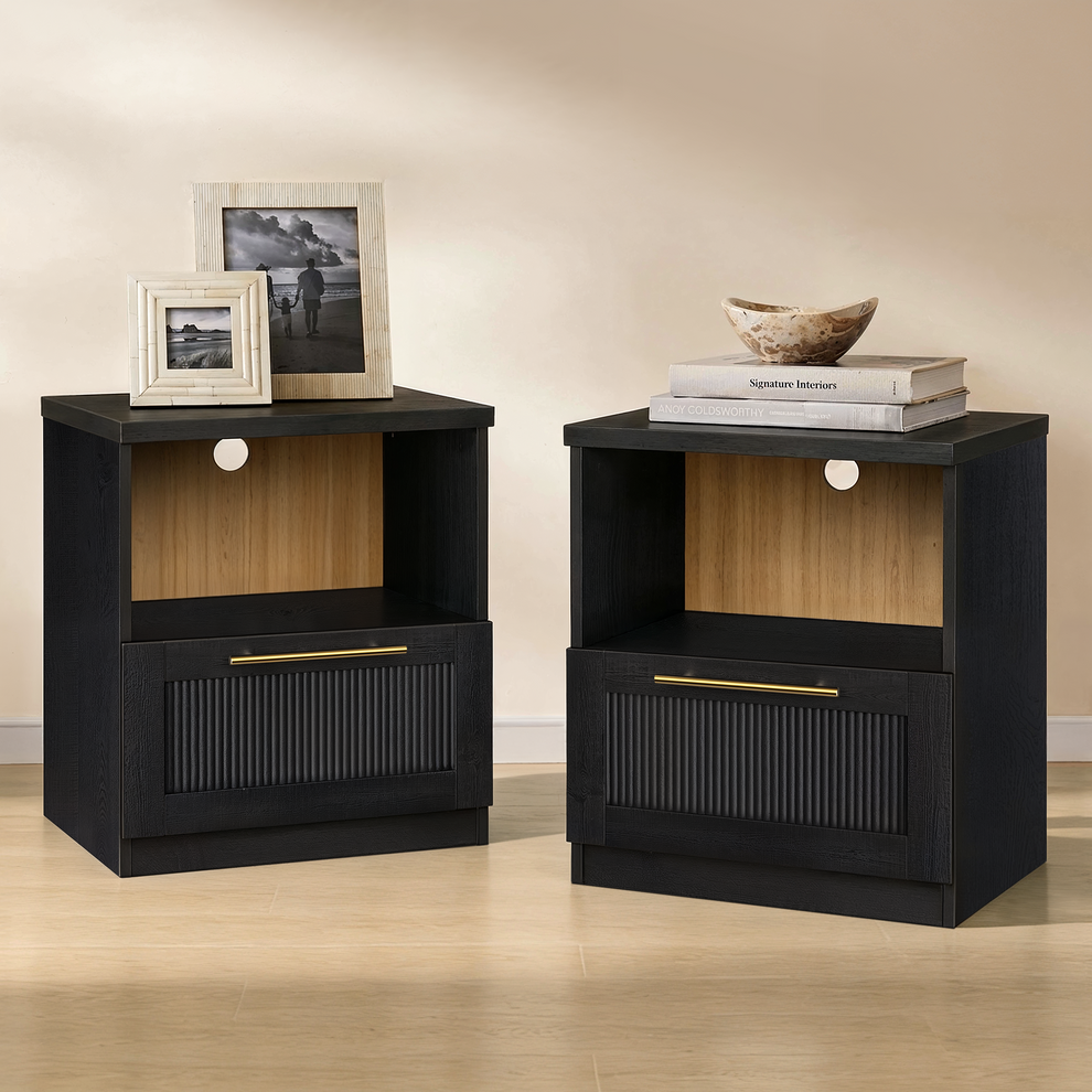 Pair of black nightstands with open wood-tone-backed cubbies and fluted lower drawers topped with gold-tone pulls