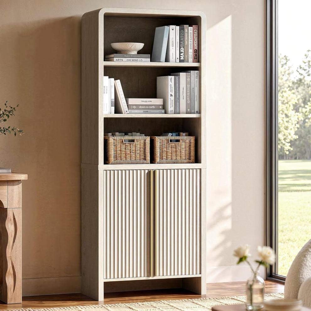 Pale bookcase with open shelves holding books and baskets above fluted double doors beside a window