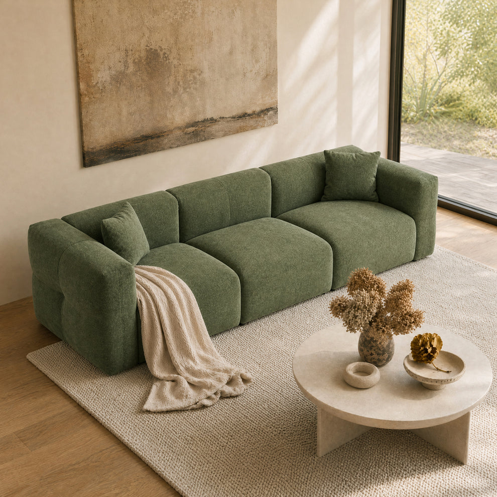 Green modular sofa with cushions and a throw in a sunlit living room