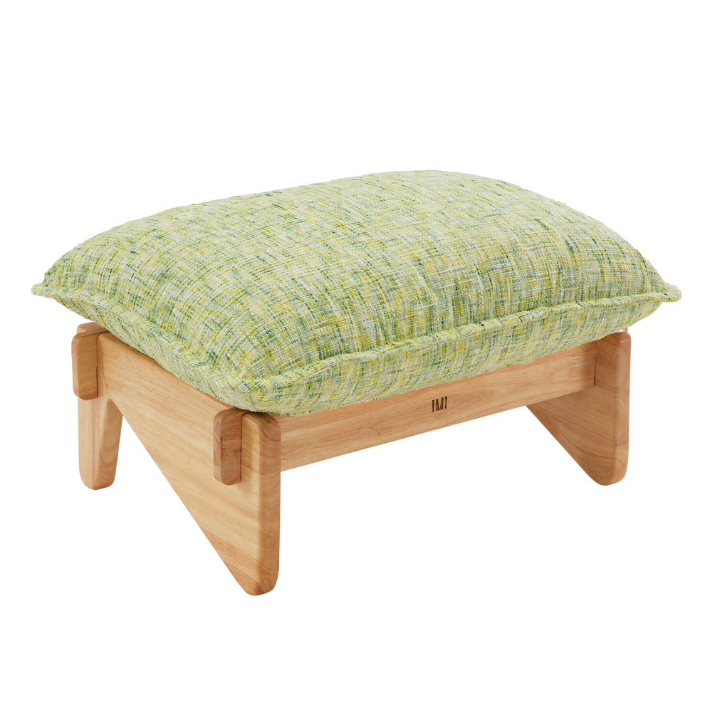 Low footstool with a thick, pale green and yellow textured cushion, piped edges, and a light brown frame with broad, rounded legs.