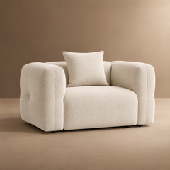Cream upholstered armchair with rounded arms and a matching square cushion.