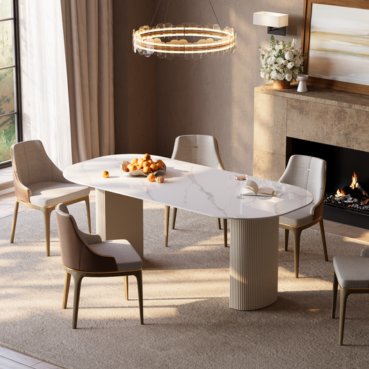 White veined dining table with a rounded rectangular top and fluted pedestal supports beside a fireplace