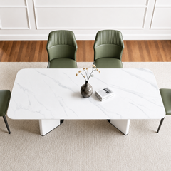 White veined dining table with rounded corners and geometric pedestal supports, viewed from above with green chairs