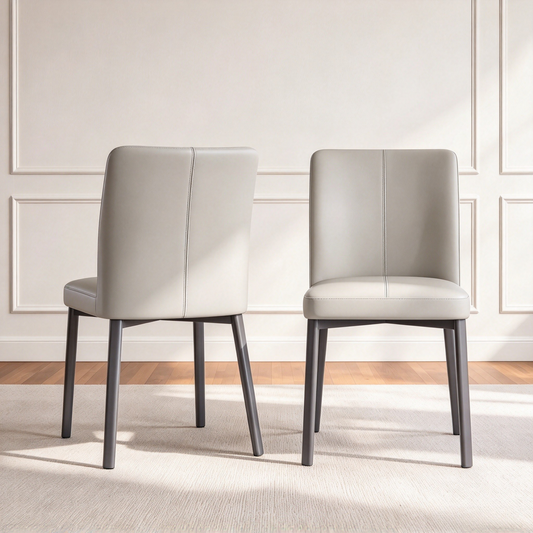 Two light gray upholstered chairs with dark legs are shown from the front and back on a rug in a bright room.
