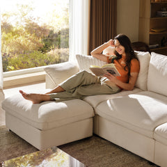 Woman reads while reclining on a light-colored sectional sofa