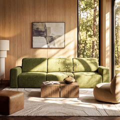 A green three-seat sofa sits in a sunlit living room with wood-paneled walls, a large window, abstract wall art, and two wood coffee tables.
