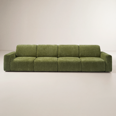 Olive green sofa with four seat cushions, four back cushions, and low rectangular arms, shown from the front against a plain cream background.