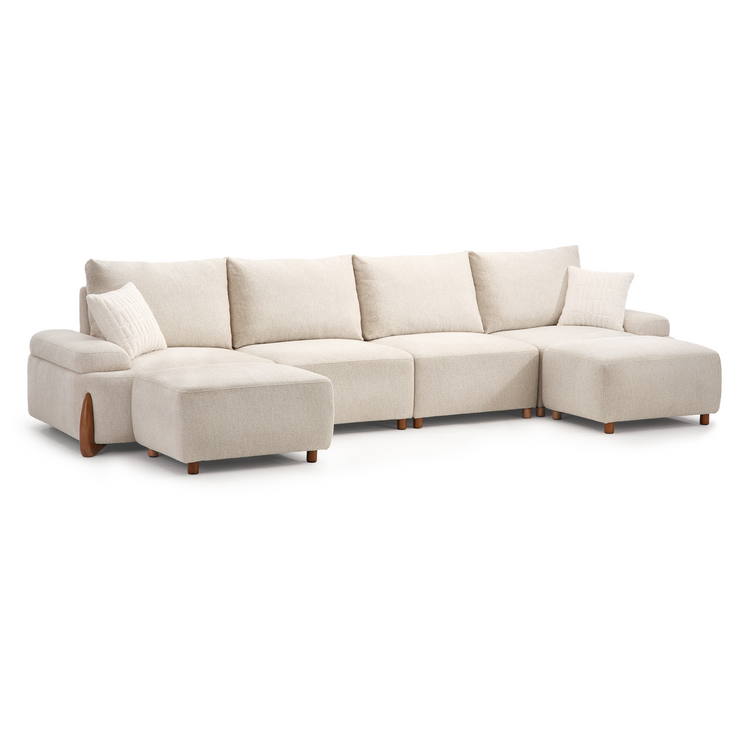 Cream-colored sectional sofa with forward-projecting seats at both ends, four back cushions, two patterned throw pillows, padded arms and short brown legs.