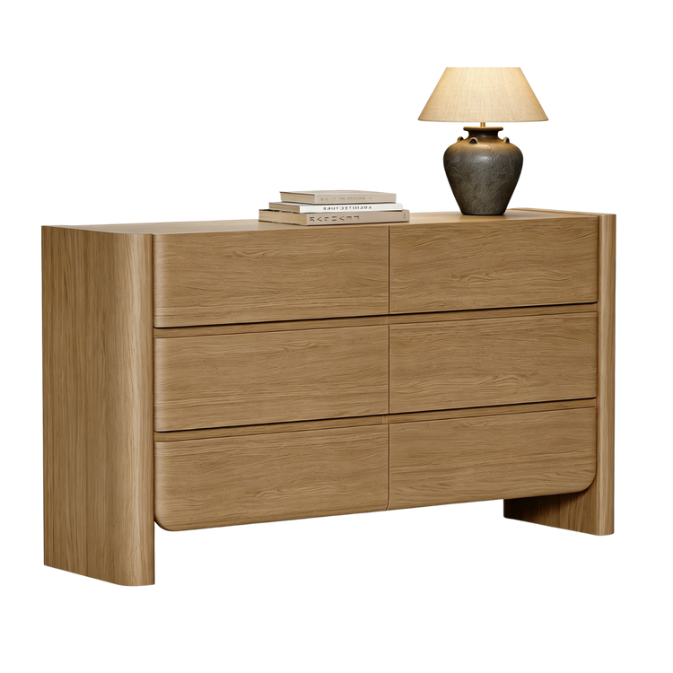 Wide light wood six-drawer dresser isolated on a black background with a lamp on top