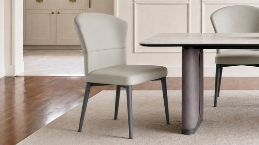 Gray curved-back dining chair stands beside a pale rounded table