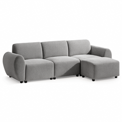 Light gray sofa with three back cushions, rounded arms, short black feet, and a matching rectangular ottoman positioned in front of the right seat.