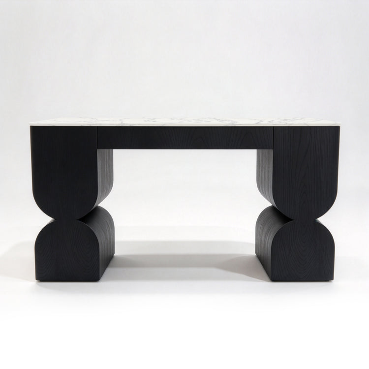 Black sculptural wood table with curved supports and a white marble-patterned top.