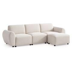 Cream-colored sofa with three back cushions, rounded arms, short black feet, and a matching ottoman positioned in front of the right seat.