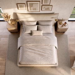 Neutral upholstered bed with layered pillows between matching wooden nightstands.
