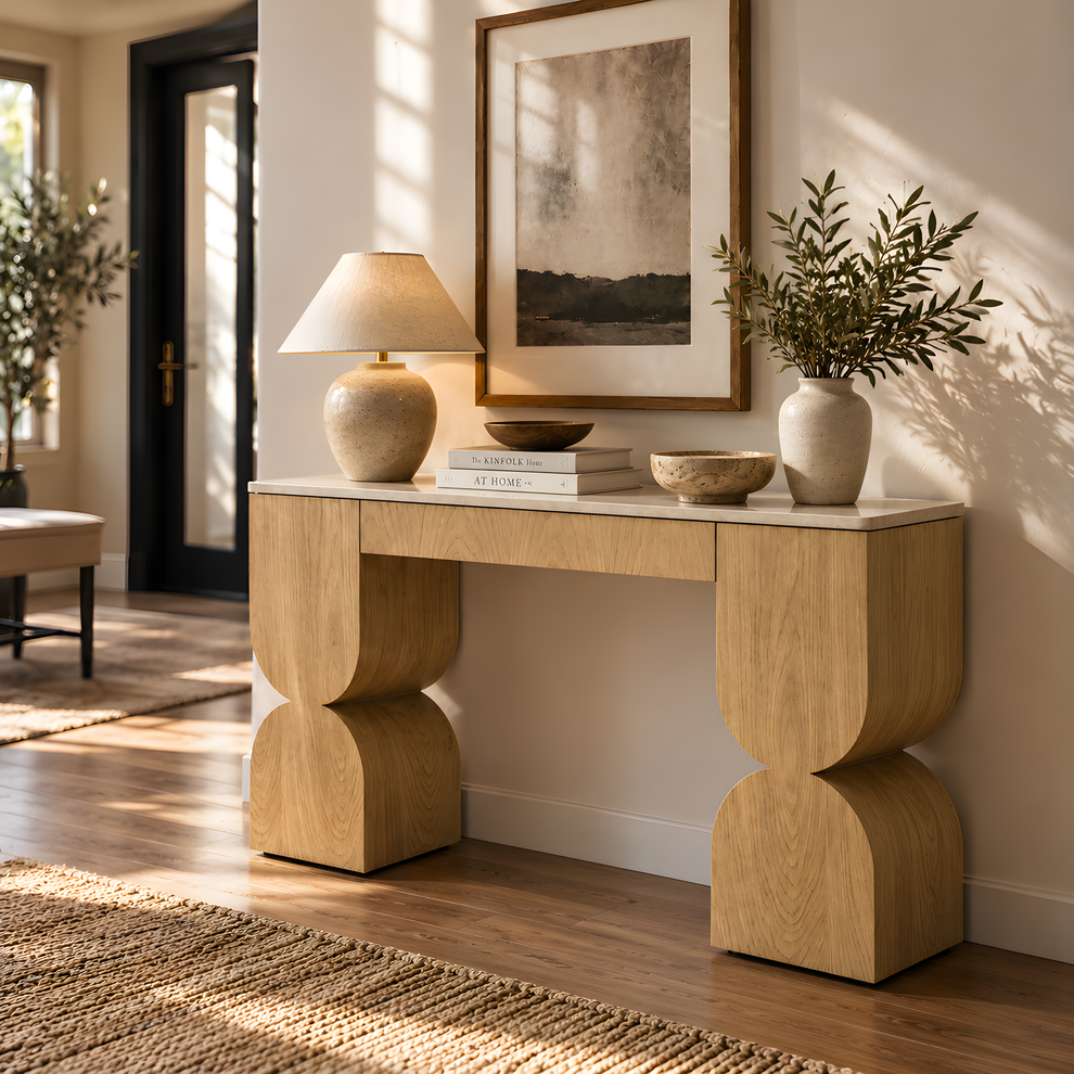 Light wood console table with sculpted legs in a sunlit entryway.
