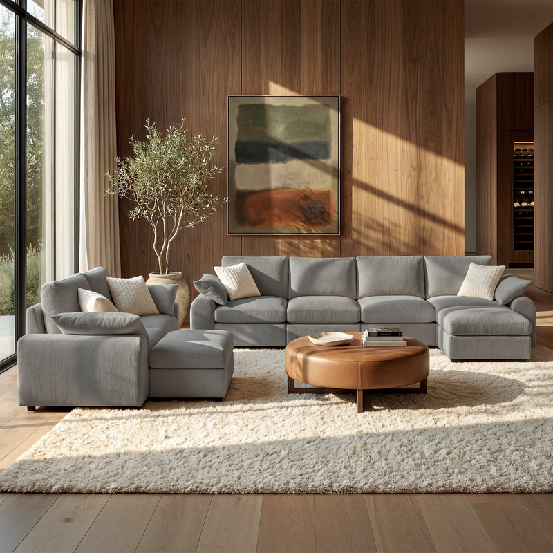 Gray modular sofa set with chaise and ottoman in a sunlit living room.