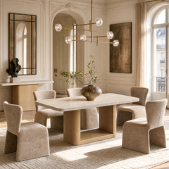 A dining table and six upholstered chairs sit beneath a branching chandelier in a sunlit room with ornate walls, a large arched doorway, and tall windows.