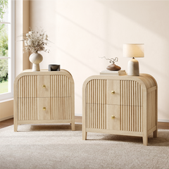 Two matching light wood-toned cabinets have rounded tops, fluted drawer fronts, and square gold-colored pulls