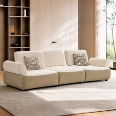 Cream modular sofa with rounded arms and two patterned pillows in a modern room