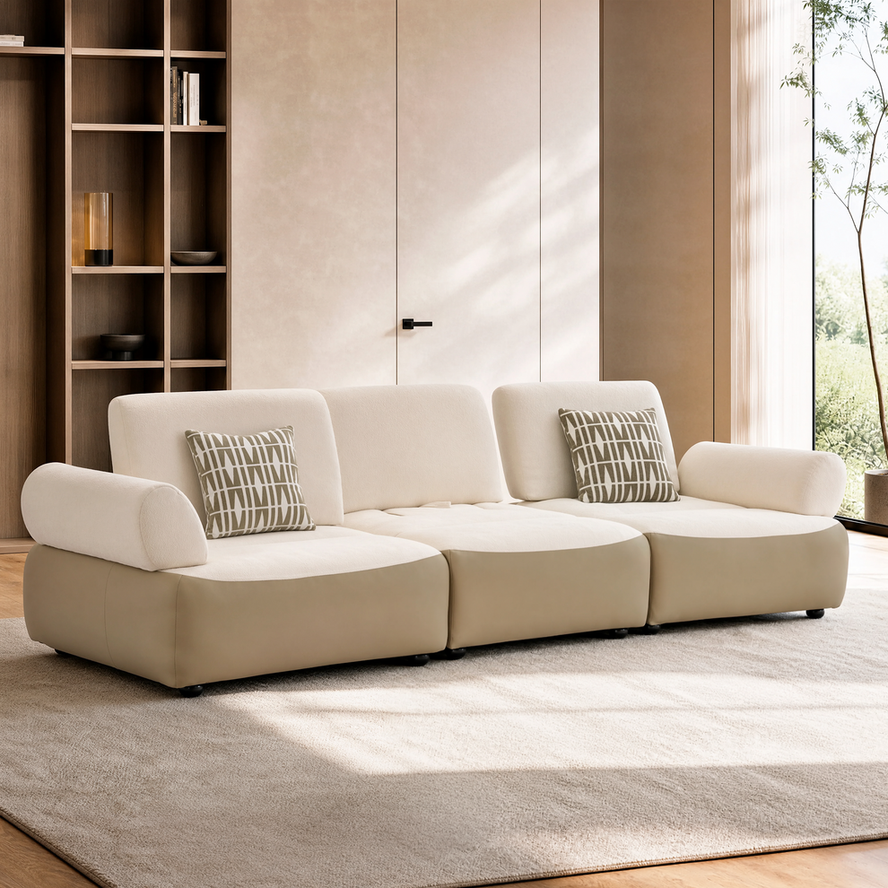 Cream modular sofa with rounded arms and two patterned pillows in a modern room
