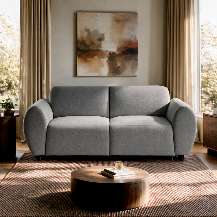 Light gray two-seat sofa with rounded arms beneath an abstract painting, flanked by curtained windows, with a round coffee table on a brown rug in front.