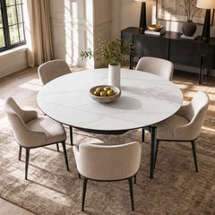Round white veined dining table with black legs and light upholstered chairs, viewed from above at an angle