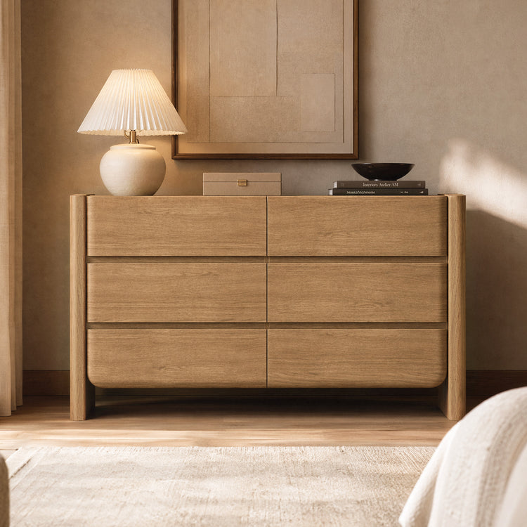 Light wood-toned chest has six broad drawers, rounded lower corners, and four legs