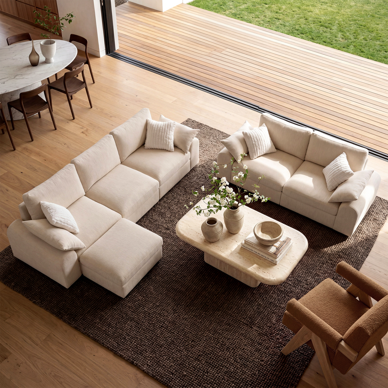 Beige modular sectional and loveseat arranged around a coffee table in a bright living room.