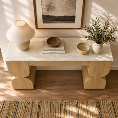 Wood console table styled with a lamp, bowls, books, and leafy branches.