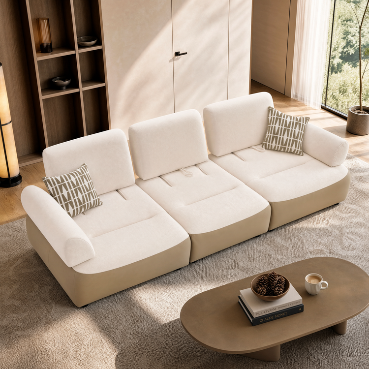 Cream modular sofa with three cushioned seats and patterned pillows in a sunlit living room.