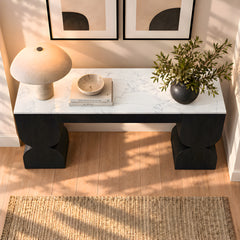 Black console table with a marble-look top, lamp, books, bowl, and leafy arrangement.
