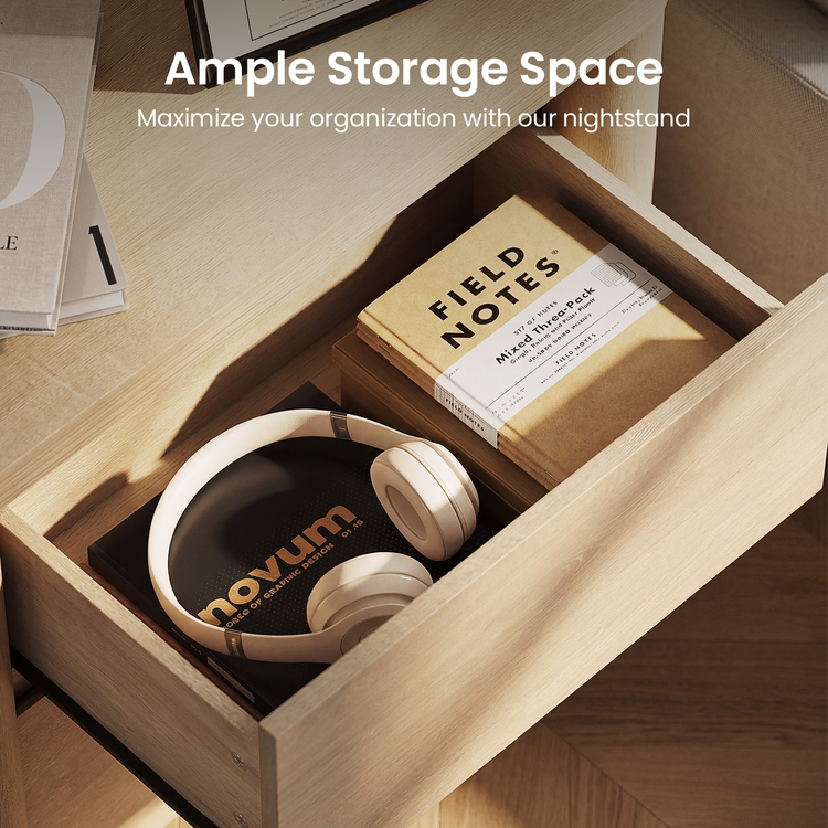 Open shallow wood drawer under a desk holds headphones and a notebook