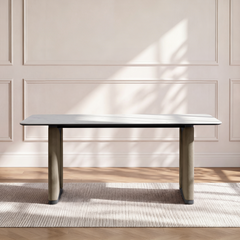 A rectangular table with a veined top and four straight legs stands against a paneled wall