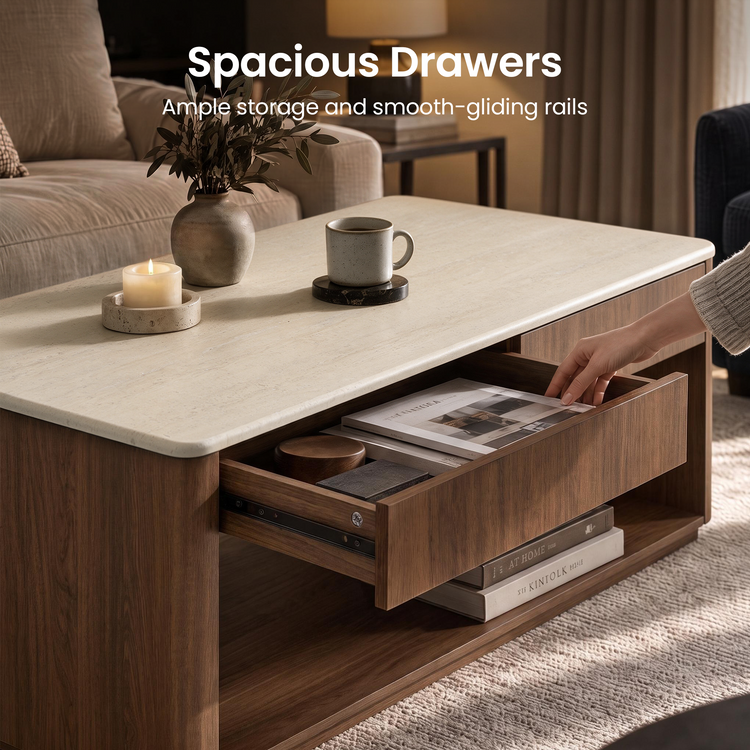 A hand opens a wooden coffee table drawer containing magazines and small objects; the table has a light-colored top and an open lower shelf.