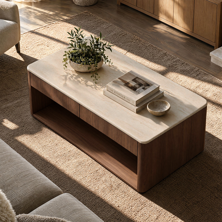 A rectangular coffee table with a pale stone top and dark wood base sits on a textured rug, holding a potted plant, stacked books, and a small bowl.