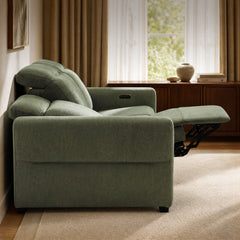 Green upholstered recliner with raised footrest in a sunlit living room.
