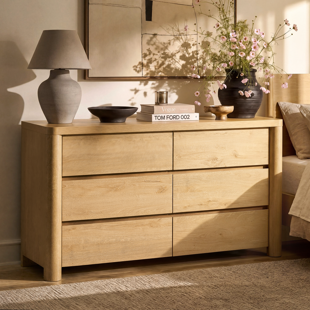 Sunlit wood-grain dresser has six handleless drawers, rounded corners, and cylindrical front legs