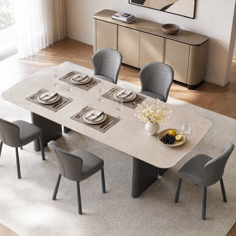 Pale rounded dining table is set for four among gray upholstered chairs