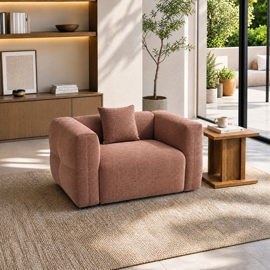 Rose-colored upholstered armchair with a matching cushion in a sunlit living room.