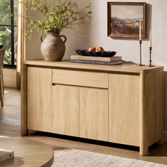 Cabinet has four doors and one wide centered drawer, Decor includes a handled vase, books, fruit bowl, and two candlesticks