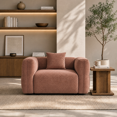 Blush upholstered armchair with matching cushion in a warmly lit living room.