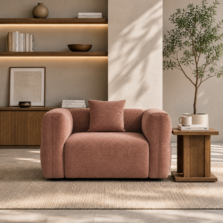 Blush upholstered armchair with matching cushion in a warmly lit living room.