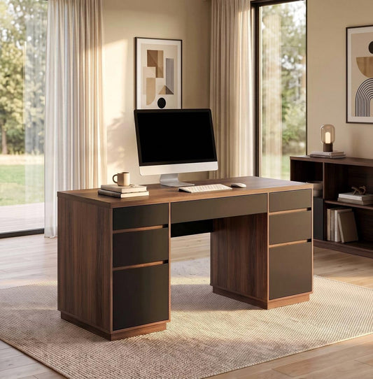 Brown wood-grain desk with dark drawer fronts on both sides and a central drawer, topped with a computer, keyboard, mouse, books and mug in a sunlit room.