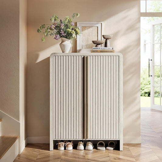 Tall pale shoe cabinet with fluted double doors and an open lower shoe space beside a staircase