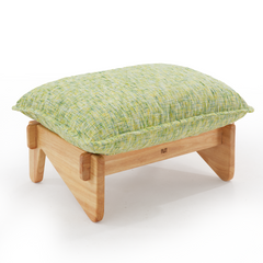 Low footstool with a light wood-toned frame, broad rounded legs, and a thick, piped cushion textured in pale green, yellow, and white.