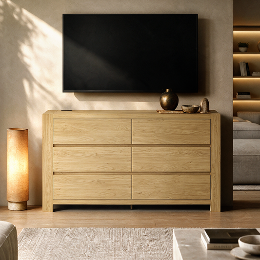 A light wood cabinet with six drawers sits beneath a wall-mounted black television in a living room, with pottery on top and a floor lamp beside it.