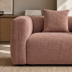 Close-up of a dusty pink textured sofa with a matching square cushion.