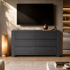 A dark six-drawer cabinet stands beneath a blank wall-mounted television in a warmly lit living room.